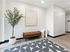 Modern apartment hallway with stylish bench, contemporary art, chic decorative rug, and a vibrant potted plant.