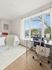 Bright and inviting bedroom with a chic desk setup and scenic window views, perfect for relaxation and productivity.