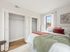 Bright and airy bedroom with a cozy bed, elegant decor, and a spacious closet, featuring large windows for natural light.