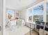 Bright, cozy bedroom with a large window offering a scenic view, featuring a comfortable bed and a modern desk corner.