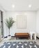 Chic and modern apartment entryway featuring a stylish brown bench, vibrant greenery in a sleek white pot, abstract wall art, and a unique minimalist side table.