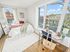 Bright and airy bedroom with large windows, cozy bed setup, and stylish desk area offering a stunning city view.