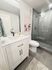 Modern bathroom with sleek glass shower, elegant vanity, and stylish artwork, designed for comfort and functionality.