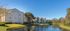 Creekside Park Apartments, exterior, river view, tan three level buildings, trees, grass