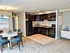 Open kitchen with dark cabinets and black appliances, full carpet