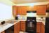 Kitchen with Black Appliances and Oak Cabinets. Coffee pot and mugs.