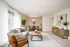 Living and dining space. Carpet. Rectangular coffee table. Artwork and plants.