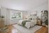 Bedroom with cathedral ceiling. green accents, plants, bed, nightstand, shelving unit.