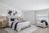 Bedroom with cathedral ceiling. navy accents, bed, nightstand, arm chair