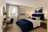 Bedroom with navy accents, window, curtains, and writing desk