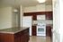 A kitchen with brown-red cabinets and white appliances. | Soaring Heights Communities Houses for Rent, Alamogordo, NM