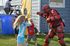 Several children holding padded clubs are smiling and attacking a man wearing red plastic armor. A blue dunk tank sits in the background. | Delta Junctions Rentals | Fort Greely rentals| DOD housing
