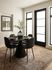 Chic dining area with a modern round table, four stylish chairs, and a decorative vase on a patterned rug.