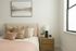 Inviting bedroom with soft-toned bedding, accent pillows, and a modern lamp on a wooden nightstand.