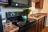 Modern kitchen with sleek appliances, elegant wooden cabinets, and stylish countertops, featuring a black stove with a teal kettle and a dual sink for convenience.