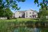 Charming residential building surrounded by lush greenery and a peaceful pond, perfect for tranquil living.