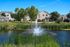 Charming residential complex surrounded by lush greenery and a serene pond with a fountain, offering a picturesque and tranquil living environment.