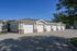 Charming residential garage units with classic white doors and brick accents under a clear blue sky.