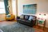 Bright and cozy living room with a modern black leather sofa, vibrant yellow armchair, and artistic wall decor, featuring stylish floor lamps and a plush area rug.