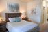 Cozy bedroom with a stylish wooden bed frame, elegant bedside lamps, and modern abstract artwork creating a harmonious and inviting atmosphere.