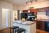 Chic kitchen with rich wood cabinetry, sleek appliances, and a stylish island, perfect for modern living.