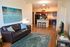 Modern open-concept living room with elegant hardwood floors, stylish kitchen with breakfast bar, and chic decor featuring a cozy brown leather couch.