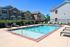 Inviting outdoor pool with sunbeds, set in a charming residential complex with brick and siding facades.