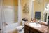Inviting bathroom with elegant decor, featuring a chic vanity, floral wall art, and cozy ambiance.