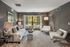 Elegant living room with modern furniture, cozy seating, and large windows offering a serene outdoor view.