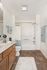Bright and modern bathroom featuring elegant tile flooring, a sleek vanity, and a stylish shower area with vibrant floral curtain.