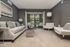 Elegant living room with plush gray sofa, modern chairs, and large windows offering scenic views, ideal for relaxation and entertainment.