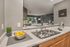 Modern apartment kitchen with sleek countertops, stainless steel sink, and open view into a cozy living room, warmly lit and inviting.