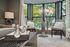 Chic living room with modern decor, large bay windows showcasing lush greenery, and cozy seating with plush cushions.