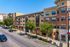 Modern urban apartment complex with stylish brick facade, lush greenery, and convenient street-level retail spaces.