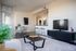 Modern living space with a sleek TV setup, a stylish coffee table, open kitchen, and a cozy dining area that invites relaxation and entertaining.