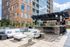 Chic outdoor lounge area with modern white seating, decorative pillows, and a stylish bar under a pergola, set against a contemporary brick building.