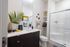 Modern bathroom with stylish vanity, elegant shower, and decorative touches including a vibrant artwork and lush plant accent.