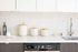 Modern kitchen with sleek white cabinetry, stainless steel faucet, and stylish hexagonal tile backsplash.