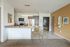 Modern kitchen showcasing sleek appliances, a stylish dining setup with golden chairs, and elegant decor in a cozy apartment setting.