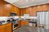 Modern kitchen with sleek stainless steel appliances, warm wooden cabinetry, and glossy countertops.