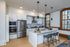 Modern kitchen with sleek stainless steel appliances, elegant pendant lighting, and a spacious island with seating by large windows.