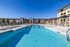 Luxurious apartment complex showcasing a sparkling outdoor swimming pool with modern lounge chairs and elegant architectural design.