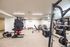 Modern, fully-equipped fitness center with weight racks, exercise machines, and ample space for workouts in a luxurious apartment complex.