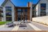 Modern apartment building with large windows and stylish outdoor seating area, perfect for relaxation and social gatherings.