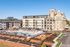 Modern apartment complex exterior with a vibrant pool area, elegant landscaping, and historical architecture in the background.