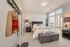 Bright and cozy bedroom featuring a plush bed with chic decor, large windows offering natural light, and stylish furniture including a soft ottoman and modern bedside lamps.