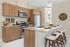 Modern kitchen with sleek wooden cabinets, stainless steel appliances, and a chic breakfast bar with stylish seating. Natural light pours in, highlighting the elegant decor and inviting atmosphere.