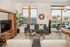 Bright and contemporary living room with large windows, chic decor, and a cozy seating area overlooking a scenic cityscape.