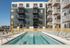 Modern apartment complex with sleek design featuring a refreshing outdoor swimming pool, surrounded by lounge chairs and vibrant balconies.