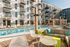 Modern apartment complex showcasing a luxurious pool surrounded by stylish loungers and chic outdoor seating, perfect for relaxing and socializing.